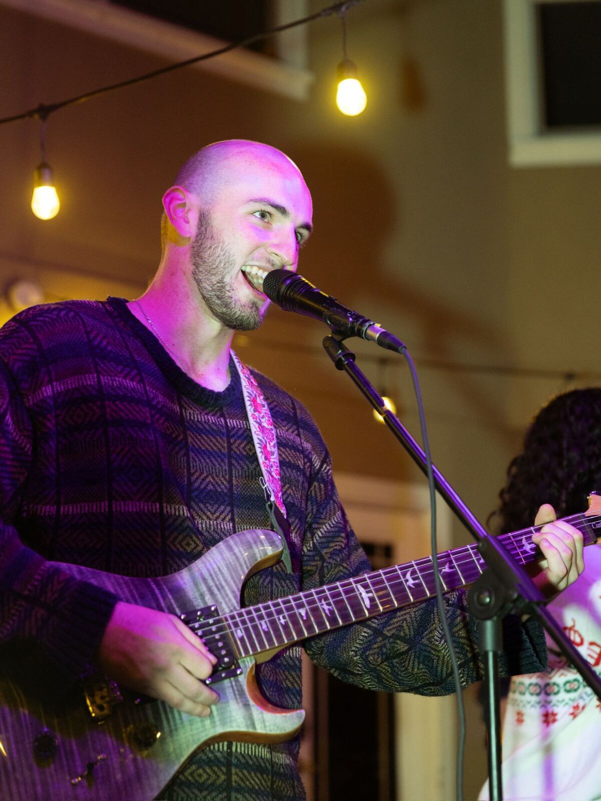 Singing and playing electric guitar at an outdoor night show